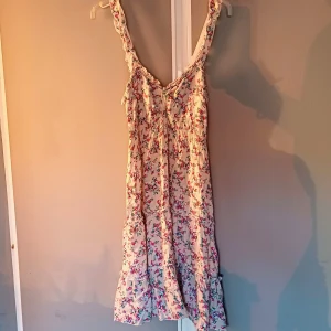 Blommig klänning från Nadasha  - Charmig blommig klänning från Nadasha i ljusa färger. Perfekt för en somrig look med sitt luftiga och bekväma material.