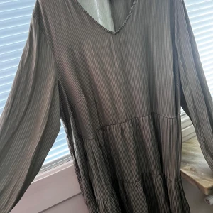 Randig klänning från Zizzi - Säljer en elegant randig klänning från Zizzi i en neutral färgton. Klänningen har en v-ringad hals och långa ärmar, perfekt för en stilren look. Den är tillverkad i ett lätt och bekvämt material som passar bra till olika tillfällen.