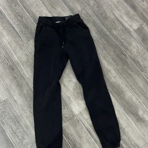 Svarta mjukisbyxor - Säljer ett par svarta mjukisbyxor med elastisk midja och snörning. Byxorna har en avslappnad passform och är perfekta för en bekväm stil. De har fickor på sidorna för extra funktionalitet.