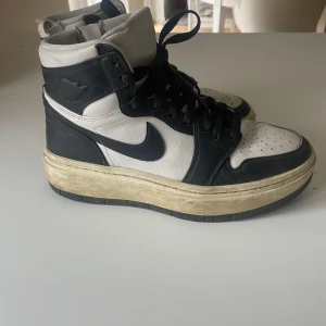 Nike Air Jordans i svart och vitt - Snygga Nike Air Jordans i svart och vitt med hög modell och klassisk snörning. Skorna har en robust sula och ikonisk Nike-logga på sidan. Perfekta för en sportig look.