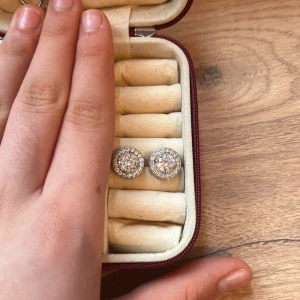 Glittriga silverörhängen - Snygga och eleganta örhängen i silver med glittrande stenar. Perfekta för att ge en touch av glamour till din outfit. Kommer i en praktisk förvaringsask.
