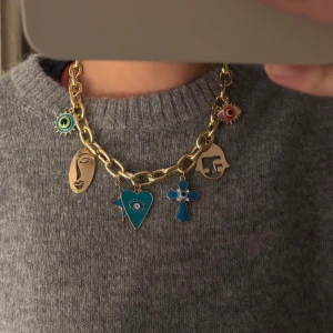 Guldhalsband med färgglada berlocker - Unikt guldhalsband med stora länkar och färgglada berlocker i olika former. Berlockerna inkluderar ansikten, ögon och geometriska former i blått, rött och grönt. Perfekt för att ge en personlig touch till din stil. Halsbandet är från Grekland, men har aldrig används. 