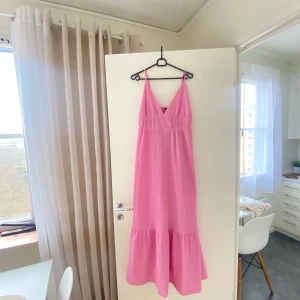 Rosa långklänning från Gina Tricot - Säljer en söt rosa långklänning från Gina Tricot. Klänningen har smala axelband och en v-ringad design som ger en feminin touch. Perfekt för sommarens varma dagar. 💖