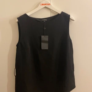 Svart ärmlös topp  - Snygg svart ärmlös topp från Stockh LM. Den har ett matchande bälte för en snygg look. 