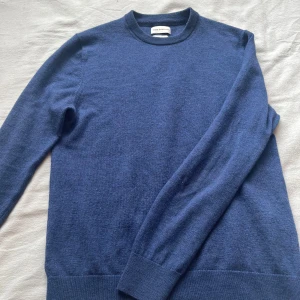 Mörkblå merinoulltröja från These Glory Days - Säljer en stilren mörkblå tröja i merinoull från These Glory Days. Tröjan har en klassisk rund hals och långa ärmar, perfekt för kyligare dagar. Den är mjuk och bekväm, idealisk för både vardag och mer uppklädda tillfällen.