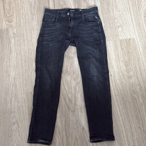 Svarta jeansbyxor från Replay - Snygga svarta jeansbyxor från Replay, modell Anbass. De har en slim fit passform och är perfekta för en stilren look. Byxorna har klassiska fem fickor och stängs med dragkedja och knapp.