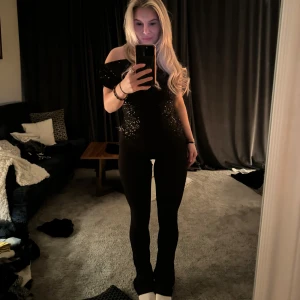 Svart offshoulder topp med paljetter - Snygg svart offshoulder topp med glittriga paljetter. Perfekt för en kväll ute eller fest.