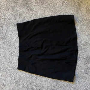 Svart kjol från H&M - Snygg svart kjol från H&M i en klassisk design. Perfekt för att matcha med olika toppar och accessoarer. Kjolen har en enkel och stilren look.