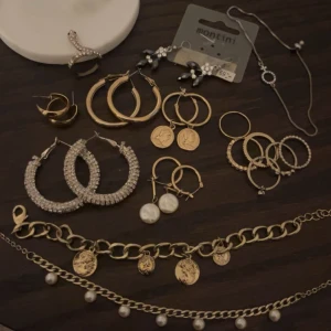 Samling av örhängen och armband - En elegant samling av smycken inklusive flera par örhängen i guld och silver. Det finns också armband med kedjor och hängande berlocker. Vissa är oanvända och vissa använda, de flesta är från hm, Gina och ur och penn❤️ man får med ett smyckeskrin✨✨