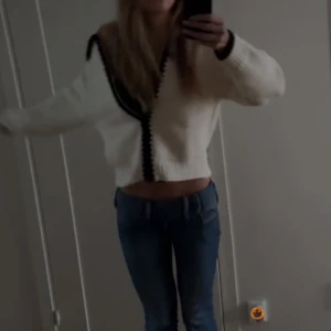 Vit kofta med svarta detaljer - Säljer en snygg vit kofta med svarta detaljer längs kanterna. Koftan har en avslappnad passform och långa ärmar, perfekt för en stilren look. Jätte bekväm