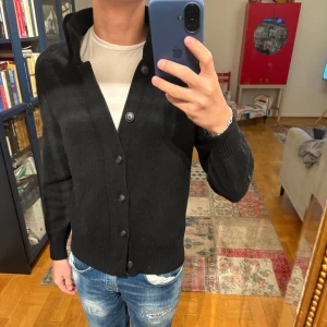 Svart kofta/cardigan från Gran Sasso - Trendig svart kofta eller cardigan från Gran Sasso med knappar framtill. Koftan är tillverkad i ull och Kashmir. Den har sällan kommit till användning så har bra skick, utan nopror. Den sitter som strl S. Nypris ca 4000