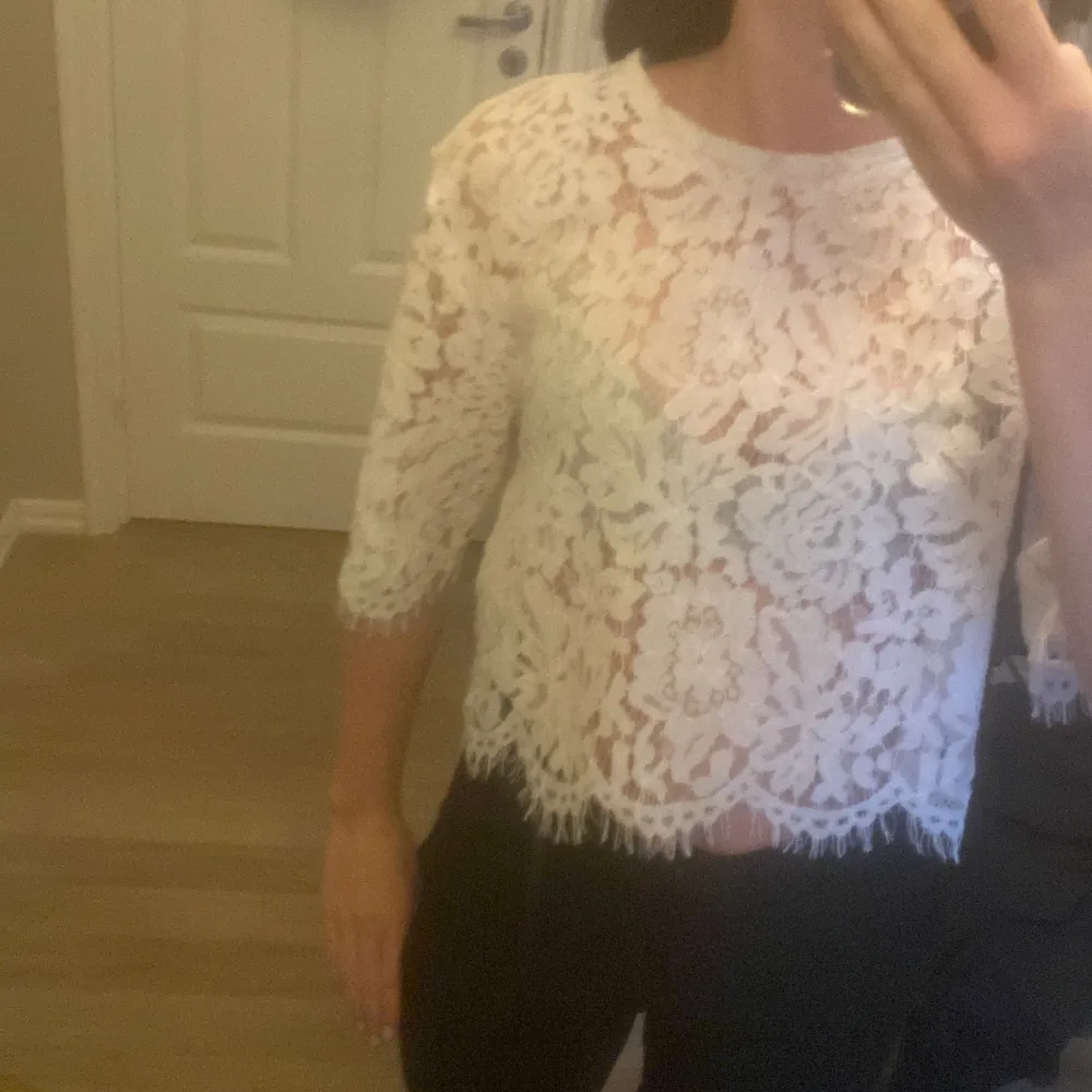 Säljer en superfin vit spetsblus från Amisu i storlek XS. Den har ett vackert blommigt mönster och är trekvartsärmad. Perfekt för en somrig look eller en festlig kväll. Blusen är croppad och ger en elegant touch till vilken outfit som helst.. Toppar.