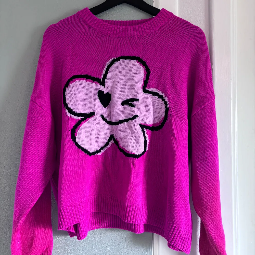 Superfin rosa stickad tröja från SHEIN med en stor, söt blomma som blinkar på framsidan. Den är perfekt för att liva upp vilken outfit som helst! Tröjan har långa ärmar och en bekväm passform. Perfekt för höst och vår.. Tröjor & Koftor.