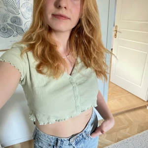 Kort&gullig topp - Grön, söt topp med gulliga detaljer och gröna knappar! För liten för mig, knappt använd! 