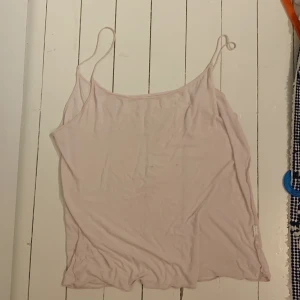 Ljusrosa linnetopp - Säljer en enkel och stilren ljusrosa linnetopp. Perfekt för sommardagar eller som ett basplagg i garderoben. Toppen är ärmlös med smala axelband och har en lös passform.