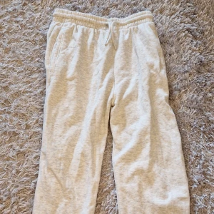 Beige mjukisbyxor från H&M Divided - Säljer ett par superbekväma gråmelerade mjukisbyxor från H&M. De är i storlek XXS och gjorda av en mjuk bomullsblandning. Perfekta för en chill dag hemma eller en snabb tur till affären. Byxorna har elastisk midja med snörning och muddar vid bensluten.