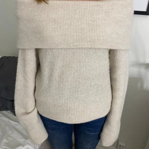 Beige stickad offshoulder tröja från H&M - Säljer en superfin beige stickad tröja från H&M. Den har en snygg offshoulder-design som är perfekt för både vardag och fest. Tröjan är i storlek S och är riktigt mysig och varm. Perfekt för höst och vinter!