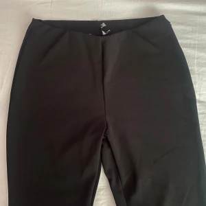 Svarta byxor - Säljer ett par stilrena svarta byxor. Perfekta för både vardag och fest. De har en enkel design med utsvängda ben och slits och är gjorda i ett mjukt material för extra komfort.