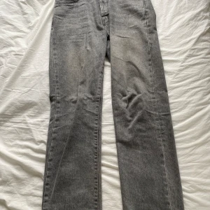 Grå jeansbyxor - Säljer ett par grå jeansbyxor i en klassisk stil. De har en rak passform och ser riktigt bekväma ut. Perfekta för vardagsbruk och kan matchas med nästan vad som helst. Byxorna har en snygg tvättad look som ger dem en cool vintage vibe.