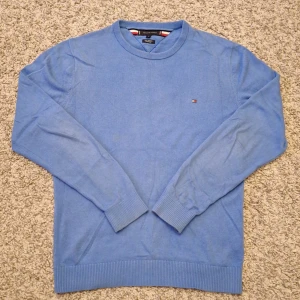 Blå jumper från Tommy Hilfiger  - Säljer denna snygga blåa jumper från Tommy Hilfiger då den inte kommer till användning mer. Den är tillverkad av Pima bomull med en kashmir blandning. Passar bra för både en mer stilig outfit samtidigt som en mer avslappnad outfit. Nypris ligger på runt 1200 kr. Modellen är ca 180 cm. Skick: 7/10