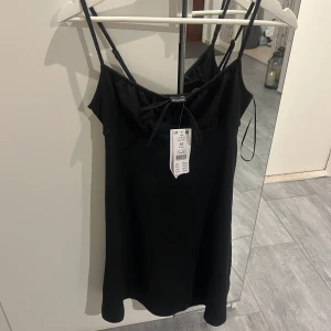 Svart klänning från Gina - Snygg svart klänning med smala axelband och knytning fram. Aldrig använd, nypris 279kr 🖤