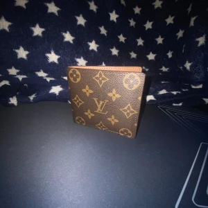 Brun plånbok från Louis Vuitton - Säljer en snygg brun plånbok från Louis Vuitton med det klassiska monogrammönstret. Plånboken är tillverkad i skinn och har flera fack för kort och sedlar. Perfekt för dig som vill ha en stilren och lyxig accessoar.Kommer inte med box🔥🍾