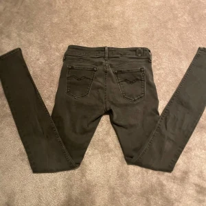 Gråa replay jeans - Snygga gråa replay jeansbyxor med slim passform. De har klassiska bakfickor med dekorativa sömmar och en knappstängning i midjan. Perfekta för en stilren look. Skick 8/10 man ser att dem varit lite använda…. Storlek W28 L30