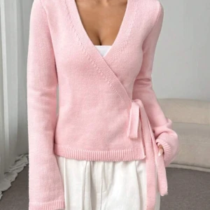 Rosa omlottkofta - Säljer en söt rosa omlottkofta med knytband i midjan. Den har långa ärmar och en v-ringad design. Perfekt för en mysig och stilren look.