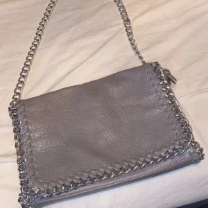 Grå/beige axelväska från scorett/tiamo - Snygg grå/beige axelväska från scorett med kedjedetaljer och dragkedja, knappt använd, inga defekter. Postar efter köp!! 💕