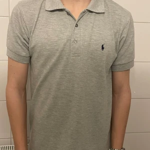 Ralph Lauren piké - Säljer en klassisk grå pikétröja från Ralph Lauren i 100% bomull. Tröjan har korta ärmar och en liten broderad logotyp på bröstet. Perfekt för en stilren look. Nypris ligger kring 1200. Mitt pris ligger på 249🍾🍾