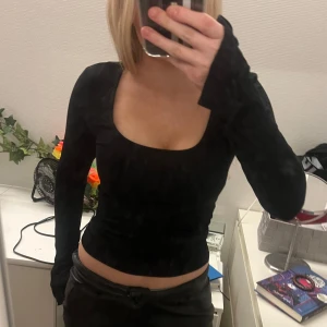 Svart långärmad topp - Snygg svart långärmad topp med djup urringning. Perfekt för en stilren look. Passar bra till både jeans och kjol.