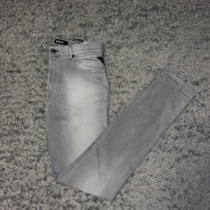 Grå jeans från Replay - Snygga grå jeans från Replay i modellen Neasan. De har en klassisk femficksdesign och en knappgylf. Perfekta för en stilren look. Storlek 32/34. Använda men i mycket bra skick. Priset går att diskutera vid snabb affär. 