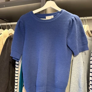 Blå stickad tröja från Vila - Säljer en snygg blå stickad tröja från Vila. Tröjan har en texturerad yta och korta ärmar, perfekt för en stilren look. Den är i storlek S och passar bra till både jeans och kjol. Perfekt för vår och sommar!