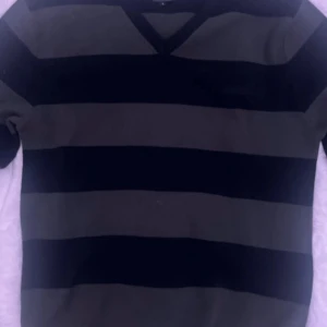 Randig tröja från Jack & Jones - Säljer en randig tröja från Jack & Jones i svart och grågrön. Tröjan har en v-ringad hals och långa ärmar. Perfekt för en avslappnad stil.