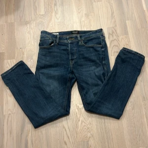 Blå jeans från Jack & Jones - Snygga blå jeans från Jack & Jones med klassisk femficksdesign och bekväm passform. De har en dragkedja och knapp framtill samt kontrastsömmar som ger en stilren look. Perfekta för en avslappnad stil.