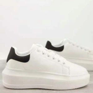 Vita platåsneakers med svart häl - Vita enkla platåsneakers från Asos. Storlek 37.  Skorna har en tjock sula som gör dom väldigt bekväma. Går nog enkelt att putsa upp samt tvätta skosnören för en ny känsla! 