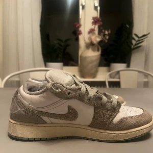 jordan 1 st 37 1/2 - Snygga jordan 1s sneakers i vitt. Skorna har en  en ljusgrön sula och suede. Perfekta för en casual look. sueden är lite fukt skadad/ gammal men ser fortfarande bra ut. PRIS KAN DISKUTERAS./ högsta bud.     250kr för boxen.               