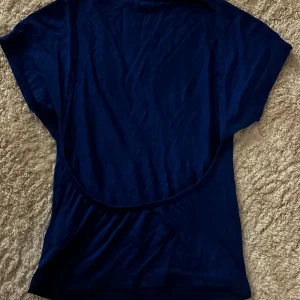 Mörkblå t-shirt - Säljer en enkel och stilren mörkblå t-shirt. Den har en normal passform och korta ärmar, perfekt för vardagsbruk. Materialet känns mjukt och bekvämt mot huden. Med öppen rygg!