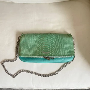 Zadig väska - Säljer äkta Zadig & Voltaire väska i en turkos färg. I bra skick men finns fåtal tecken på användning. Kommer med två kedjor, en längre och en kortare. Även dustbag medföljer. Skriv gärna vid intresse 