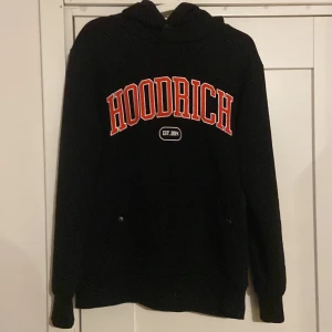 Svart hoodie från Hoodrich - Säljer en svart hoodie från Hoodrich i mycket bra skick. Perfekt för höst och vinter med sin mysiga passform. Har praktiska fickor med dragkedja vid armen. Passar perfekt för en avslappnad stil!