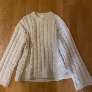 Beige stickad kabeltröja - Hm - Mysig beige stickad tröja med kabelstickat mönster. Perfekt för kyliga dagar med sin varma och bekväma passform. Tröjan har långa ärmar och ribbade kanter vid ärmslut och nederkant. 