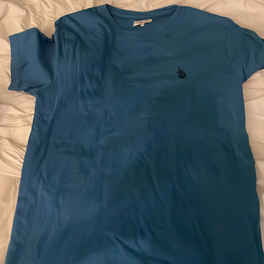 Säljer en snygg blå t-shirt från U.S. Polo Assn. i bra skick. Den har en liten broderad logga på bröstet och är perfekt för vardagsbruk. T-shirten är kortärmad och gjord i mjukt bomullsmaterial. Passar perfekt till både jeans och shorts! Skriv vid köp eller frågor ✝️😀. T-shirts.