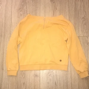 Gul tröja med dragkedja - Säljer en snygg gul tröja i mycket bra skick. Den har en liten dragkedja framtill och långa ärmar. Perfekt för höst och vår, och den är superbekväm att ha på sig. Passar både till vardags och lite mer avslappnade tillfällen. 🌟