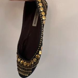 Steve Madden ballerina skor - Stl 39 ballerina skor från Steve Madden i svart med guldiga detaljer. Alla pärlor och detaljer på skorna är i blandat material men de lite större plattorna är i metall. Lite har åkt upp på höger fot framsida som sista bilden visar. Säljer pga storlek