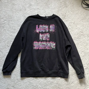 Svart tröja med tryck - Svart tjocktröja med ett rosa-lila tryck på. Storlek S men oversize!