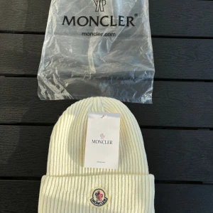 Moncler Mössa - Jätte fin Moncler mössa som är mjuk och varm vilket passar bra till användning i hösten och vintern. Mössan har den fina Moncler loggan broderad på framsidan. Allt på bilden ingår. Dm vid intresse!