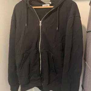 Svart hoodie med dragkedja från Uniqlo - Säljer en svart hoodie från Weekdayi storlek M. Den har en dragkedja framtill och en skön huva med dragsko. Perfekt för höst och vår, eller bara att mysa i hemma. Den är i bra skick och superbekväm!