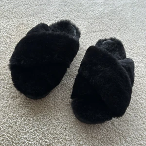 Svarta fluffiga lyx-tofflor från INUIKII - Mysiga, lyxsnygga, svarta tofflor från INUIKII storlek 39. Perfekta för att hålla fötterna varma och bekväma hemma. De har en korsad design på ovansidan och en stabil gummisula. Perfekta för kalla dagar när du bara vill mysa runt hemma och se bra ut!