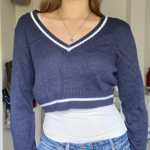 Croppad marinblå tröja - Stickad v-ringad tröja i kort modell, marinblå med vita detaljer. Storlek L på lappen men passar S/M