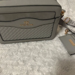 Väska, River Island👜 - Säljer denna fina axelremsväskan från River Island som jag köpt från Zalando men som bara står på hyllan. Rymlig och perfekt i storlek med avtagbara tjockare band och även korthållare till. Använt 2 gånger, nyskick🤍